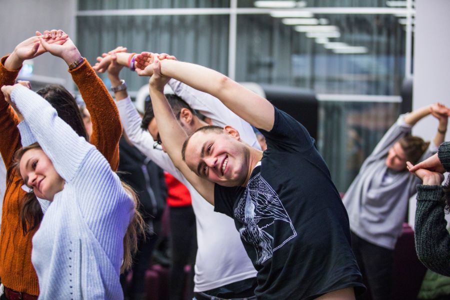 Opiskelijat ovat nostaneet kädet ylös ja tekevät kylkitaivutusta.