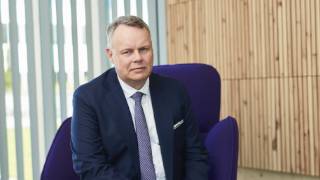 Dean of the Faculty of Social Sciences Juho Saari sits on a purple chair and looks at the camera.