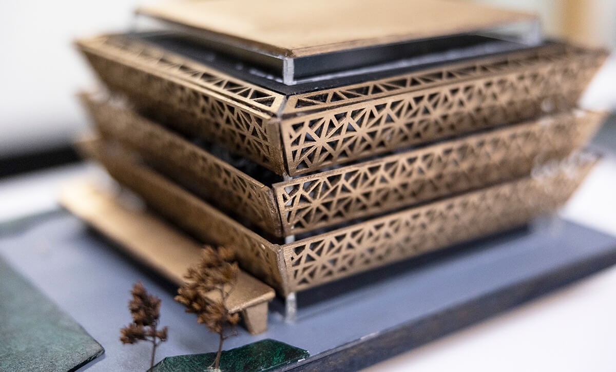 A bronze-painted miniature model of a modern building in a close-up picture.