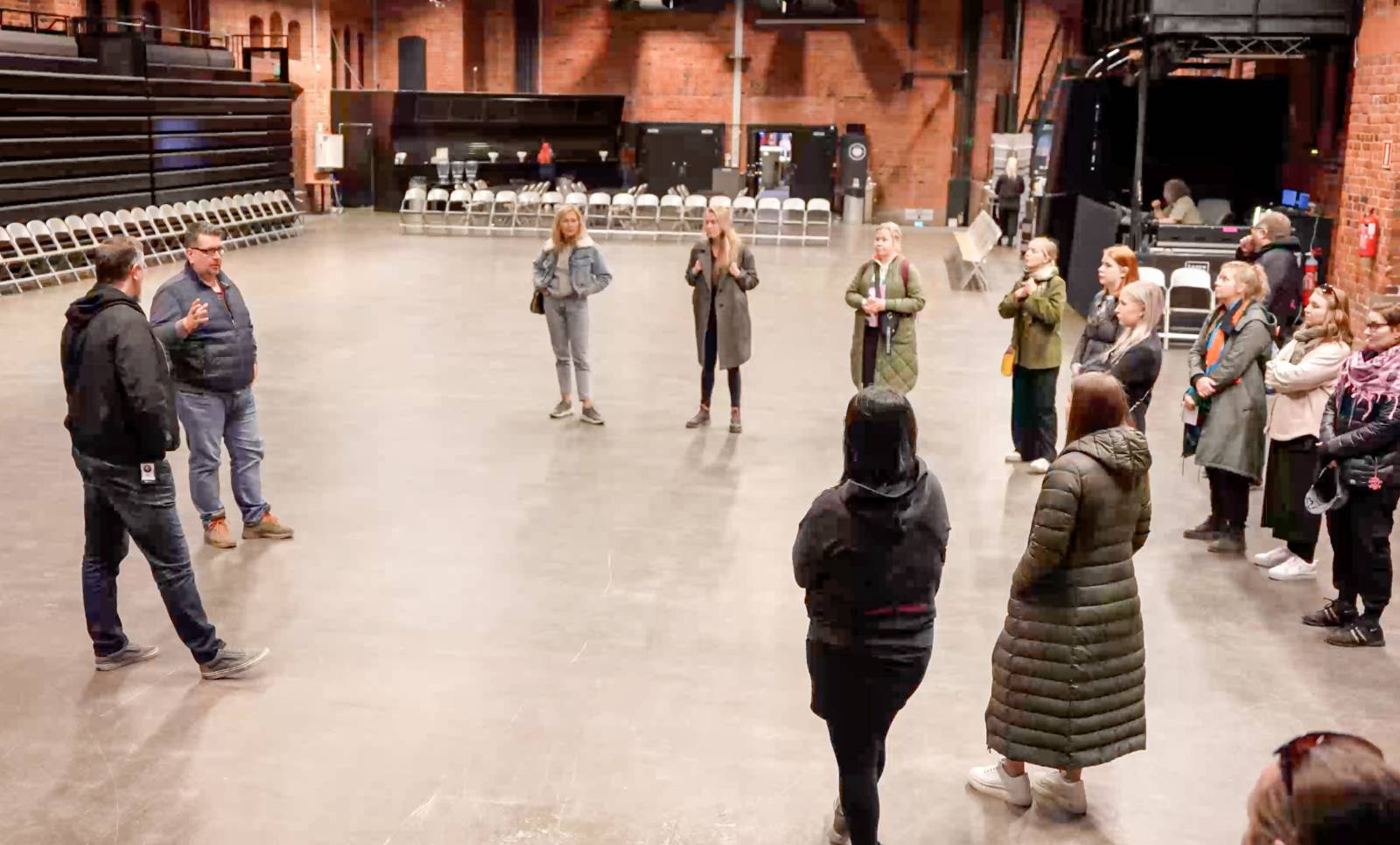 Ryhmä opiskelijoita kuuntelee opettajan puhetta