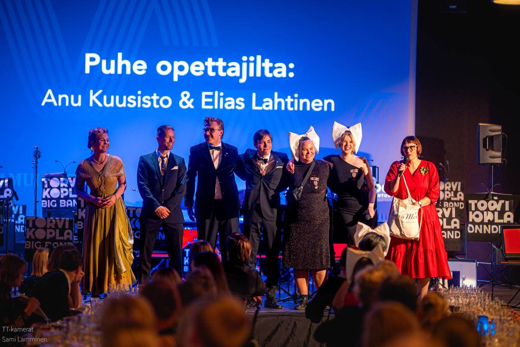 Joukko nuoria koolla juhlapaikan esiintymislavalla.