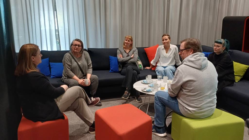 Ihmisiä istumassa sohvilla ja tuoleilla