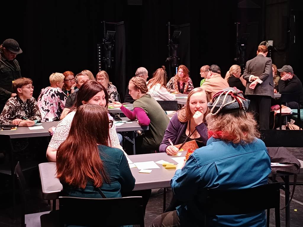 Ihmisiä istumassa pöytien äärellä. Luovien alojen tuottajaverkoston avajaiskiertue Kuopiossa 14.4.2026.