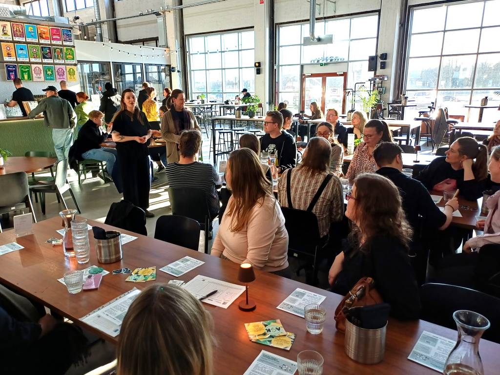 Ihmisiä istumassa pöydissä. Luovien alojen tuottajaverkoston avajaiskiertue Oulun Varikko Panimolla. 