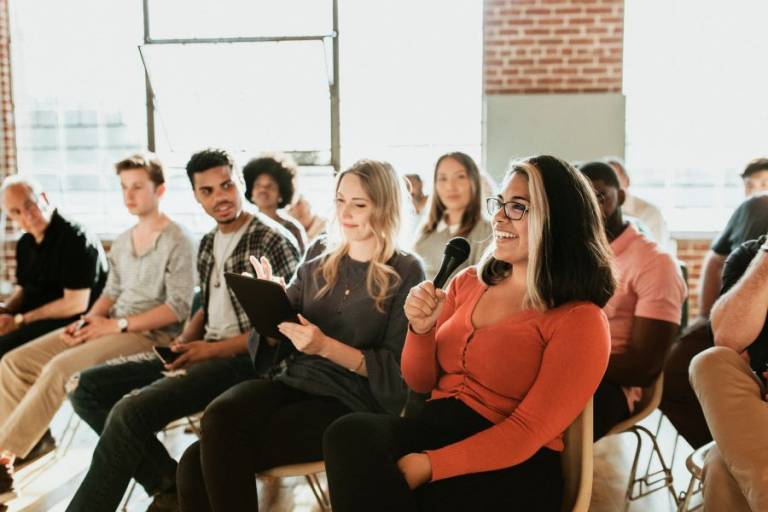 Ryhmä aikuisia istumassa yleisönä keskustelutilaisuudessa.