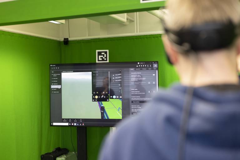 Kuvassa näkyy ihmisen selkää ja päätä. Hänellä on yllä XR-lasit. Ihmisen edessä on näkyvillä ruutu, jossa näkyy hänen näkemänsä virtuaalitodellisuus.