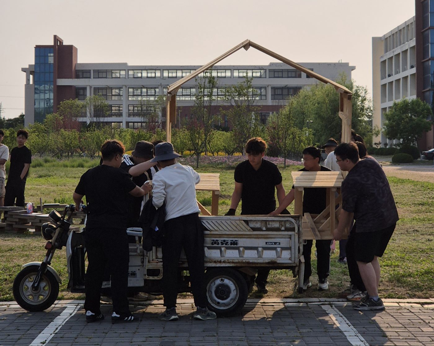 Opiskelijat kuljettavat paviljongin osaa puutyöverstaalta rakennuspaikalle.