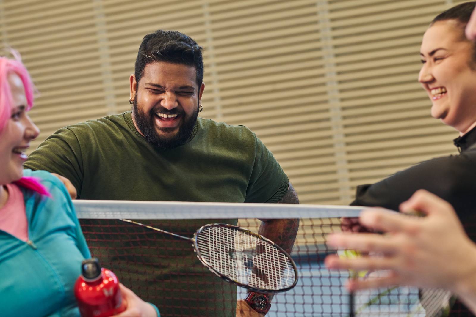 Iloisia opiskelijoita sulkapalloverkon ympärillä.