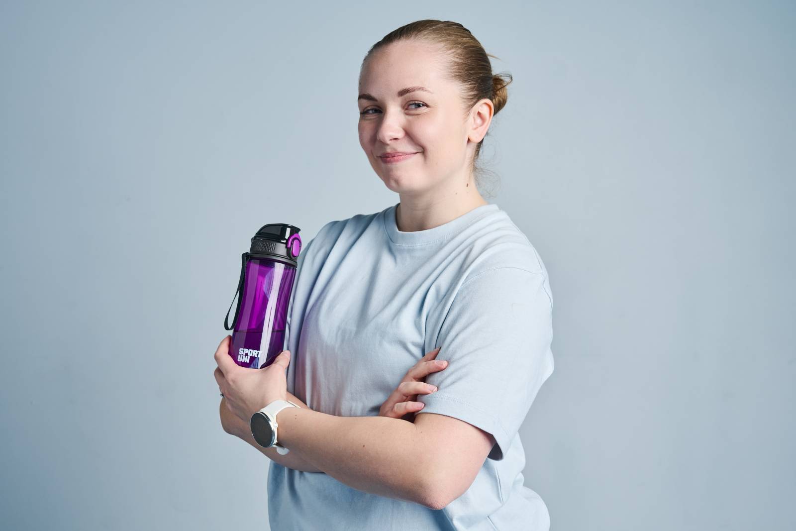 Opiskelija poseeraa juomapullon kanssa.