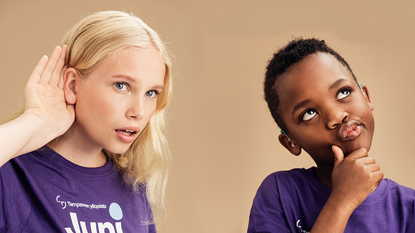 Valokuva, jossa tarkkaan kuunteleva nuori sekä mietiskelevä lapsi Juniversityn t-paidat päällä.
