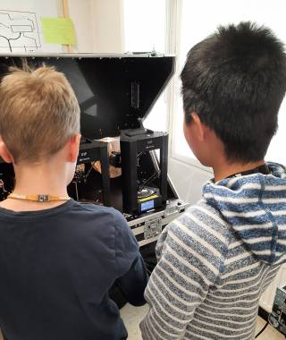 Valokuva lapsia katsomassa 3D tulostusta.