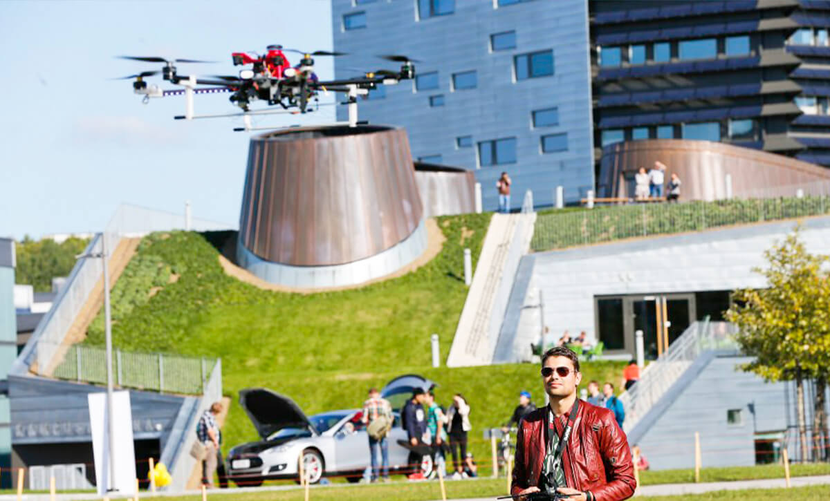 Mies lennättää aurinkoisena päivänä dronea Hervannan Kampusareenan edessä.