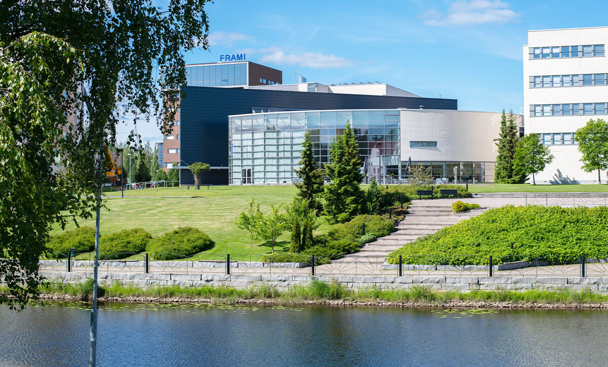 Seinäjoen yliopistokeskuksen rakennus vehreässä aurinkoisessa maisemassa joen varrella.