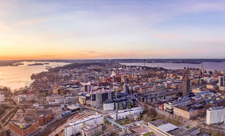 An aerial view of the city centre of Tampere. Lake Pyhäjärvi is on the left side and Lake Näsijärvi is on the right side. In the foreground are the university buildings on the city centre campus and Nokia Arena.