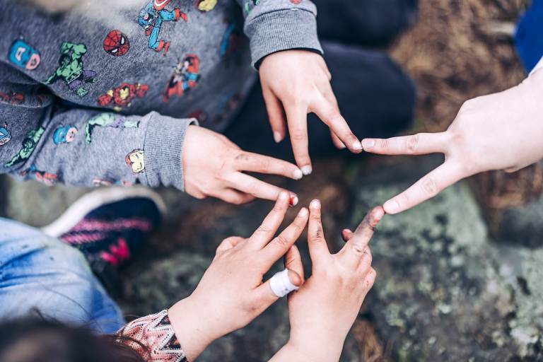 Lasten käsiä, jotka muodostavat sormet yhteen liittäen tähtimäisen kuvion.