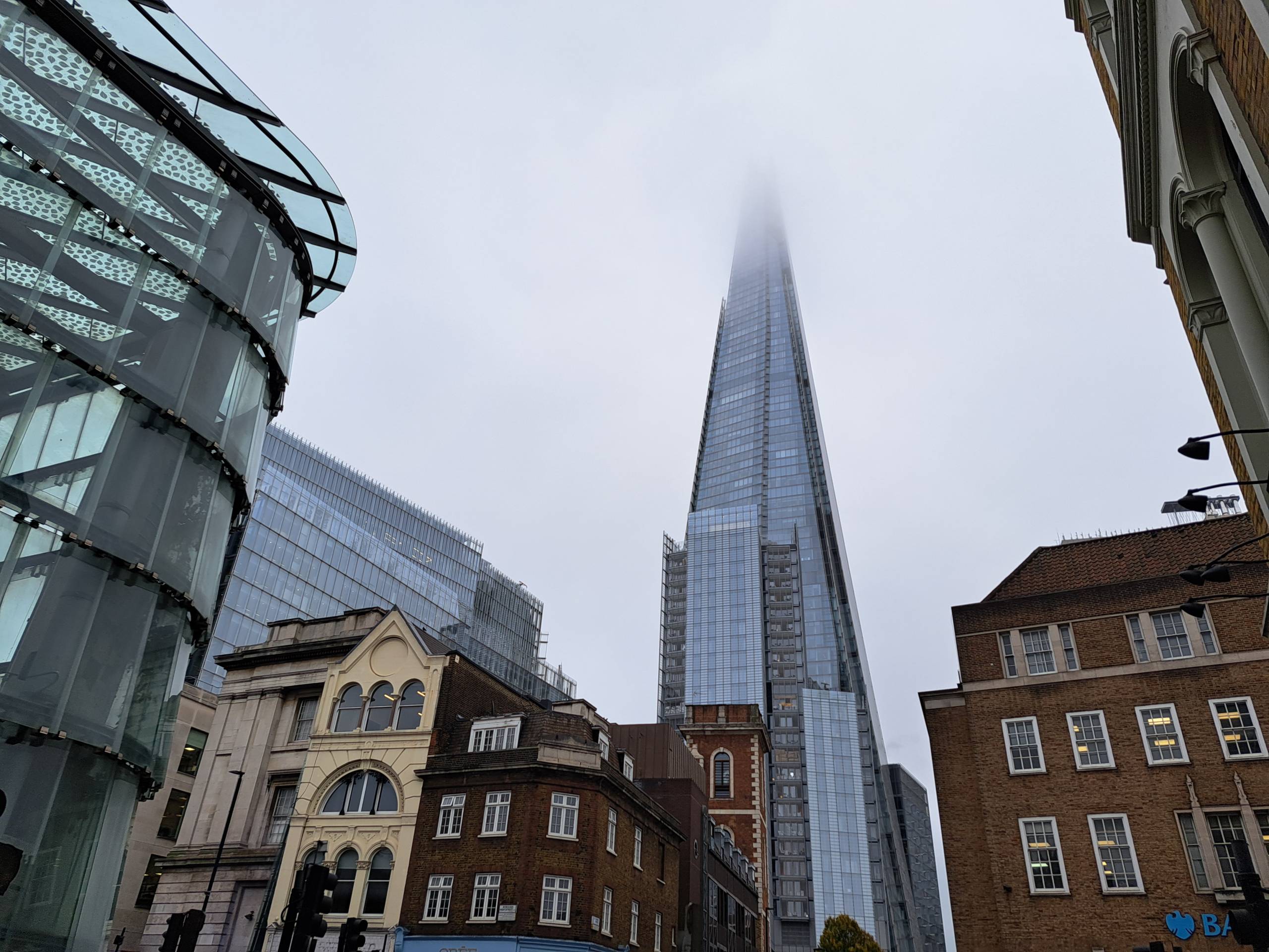 Shard kuvassa keskellä, yläosa on sumun peitossa. Muoto on kuin terävä sirpale kohti taivasta.