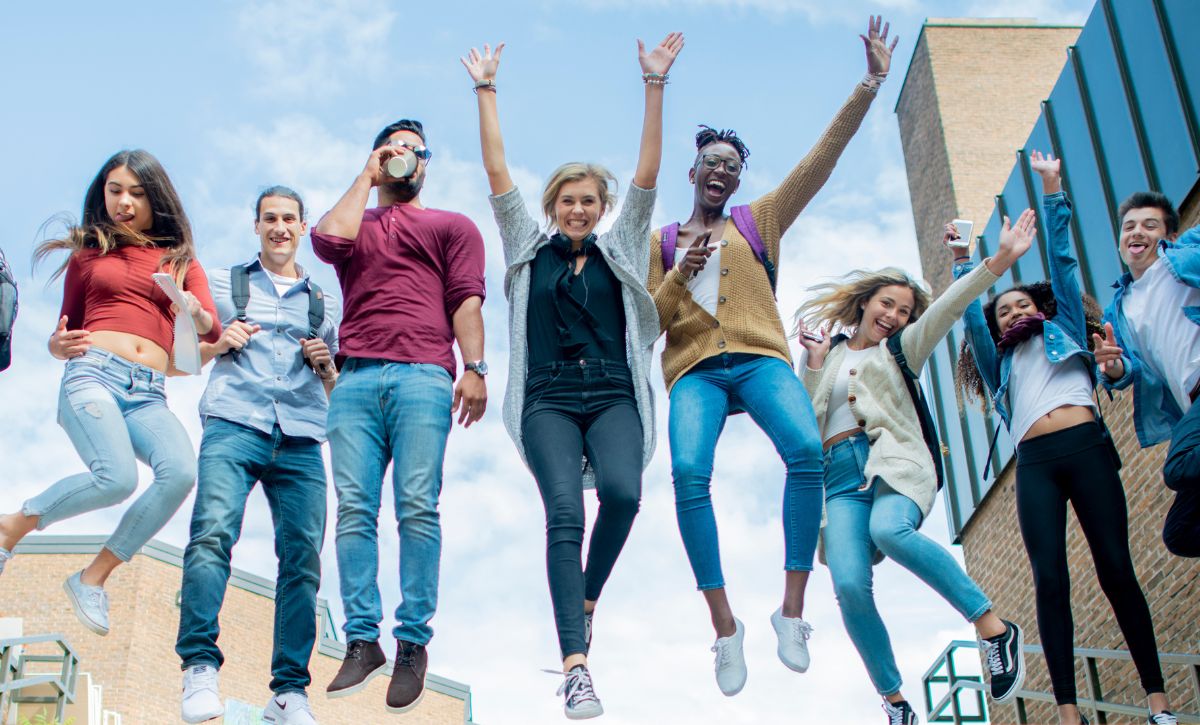 Happy students jumping outdoors